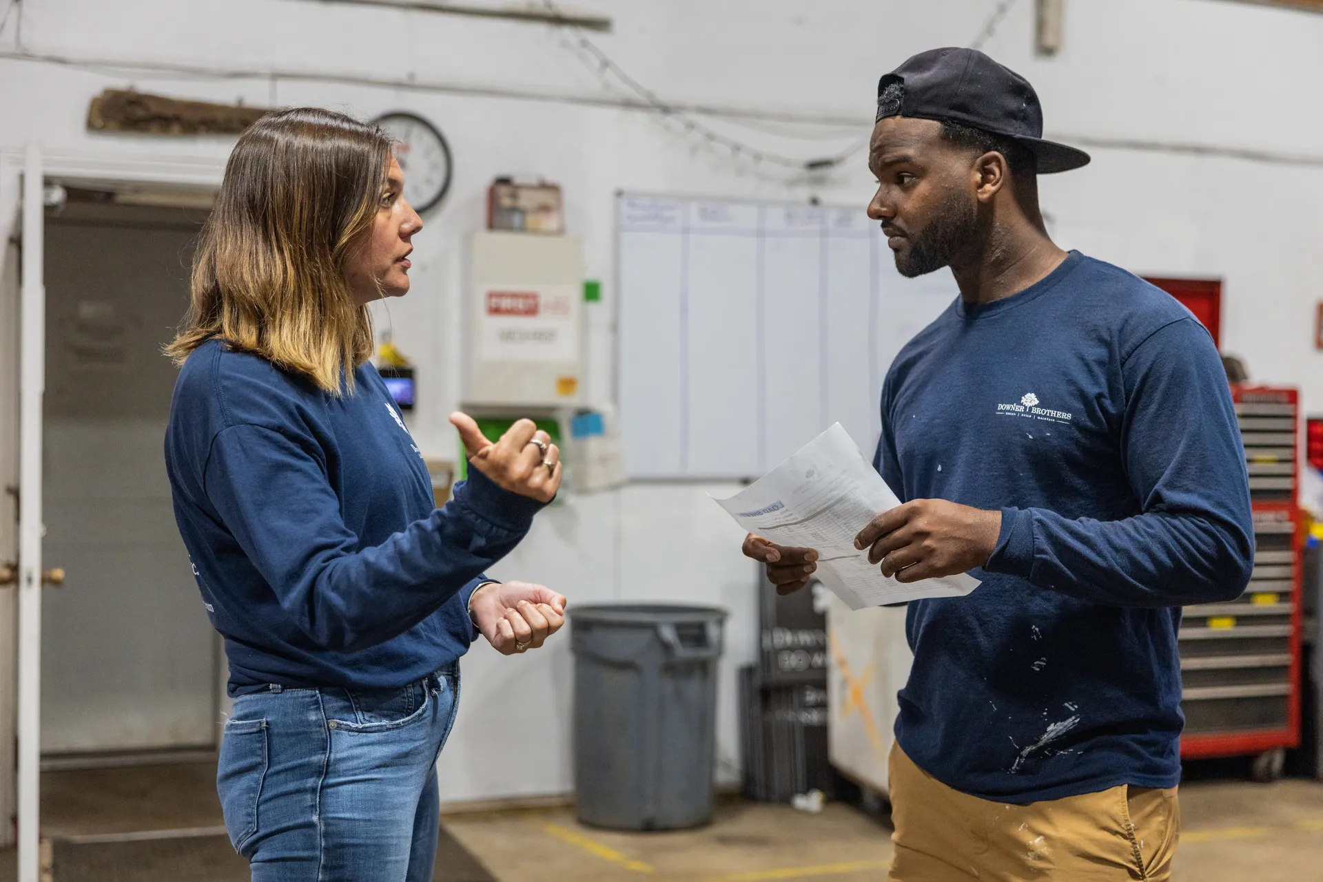 An office manager and a crew leader talk through a work order in the shop.